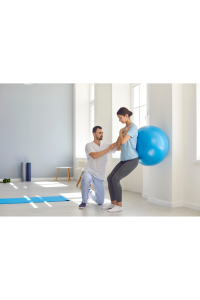 Imagen de un fisioterapeuta con una paciente realizando ejercicio apoyada en pelota grande.